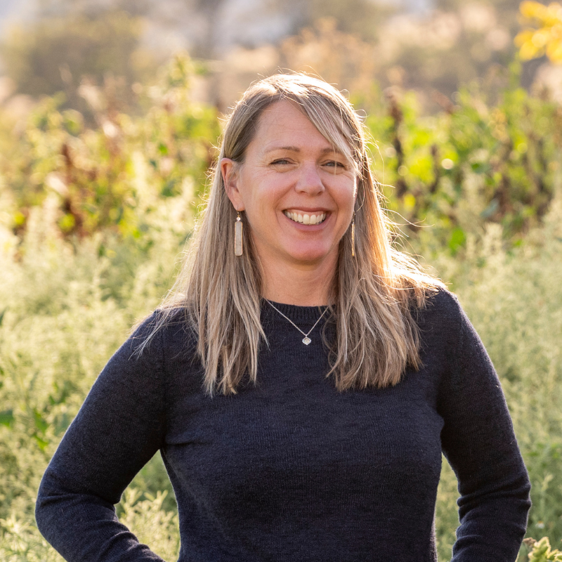 Victoria Whisman, MFT, licensed therapist at A Place to Exhale, smiling outdoors in a sun-warmed vineyard setting