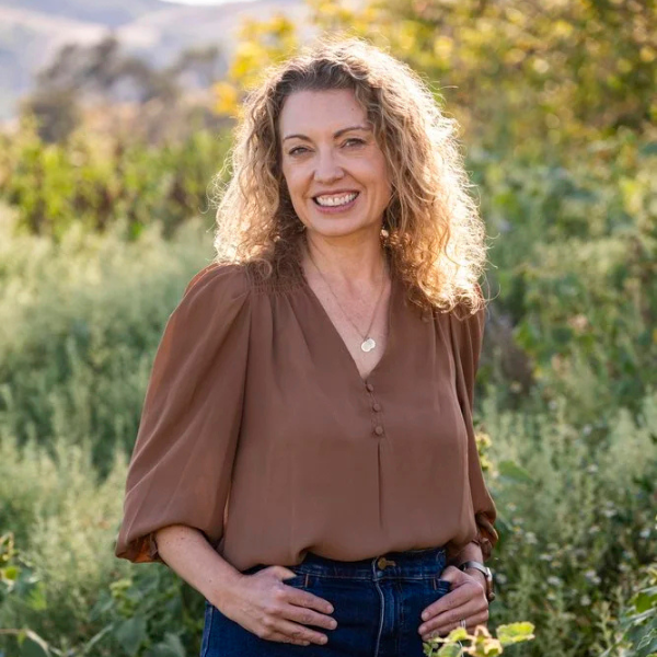 Jamie L. Katoff, LMFT, smiling outdoors in a brown blouse with curly hair and a natural green hillside background